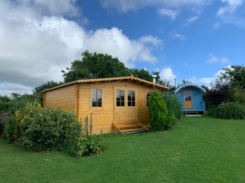 a small wooden cabin in a grassy yard at Coutts Glamping in Wadebridge