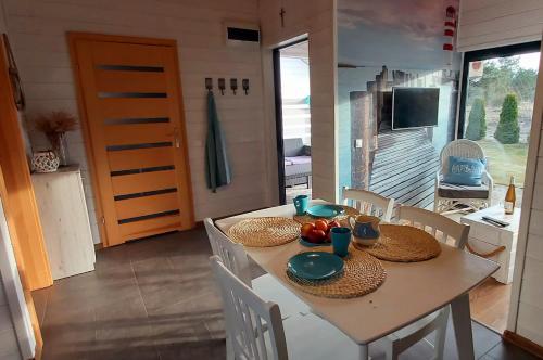 a dining room with a table and chairs and a television at Balfala domki nad morzem in Ostrowo