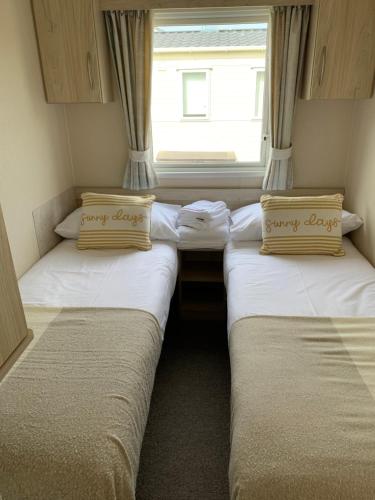 two beds in a small room with a window at Newquay Bay Resort 63 in Newquay Bay Resort