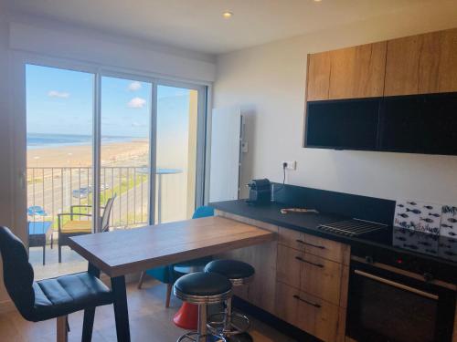 une cuisine avec une table et une vue sur l'océan dans l'établissement 180° vue océan, T3 marin haut de gamme, à Saint-Jean-de-Monts