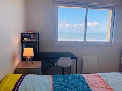 une chambre avec un lit, une fenêtre et une chaise dans l'établissement 180° vue océan, T3 marin haut de gamme, à Saint-Jean-de-Monts