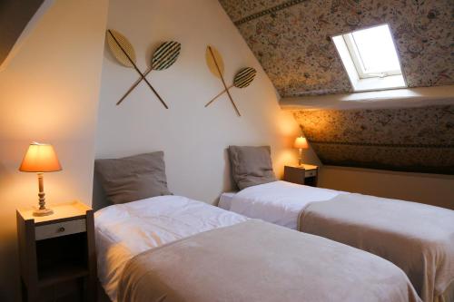 deux lits dans une chambre d'hôtel avec une fenêtre et une fenêtre dans l'établissement Le relais d'Eugénie Maison d'hôtes en forêt d'Orléans, à Courcy-aux-Loges