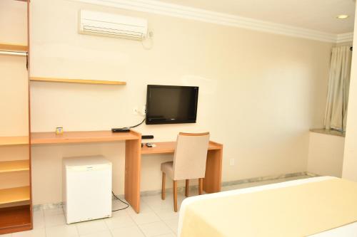 a room with a desk with a computer and a tv at Troodon Park Hotel in Sousa