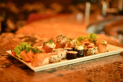 a plate of food with sushi and vegetables on a table at Troodon Park Hotel in Sousa