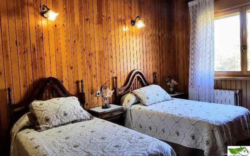 1 dormitorio con 2 camas, ventana y paredes de madera en Casa Vacacional Mari Paz en Llanes