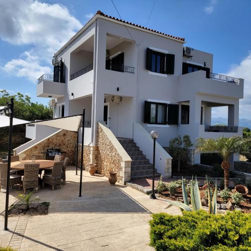 Casa blanca con mesa y patio en Paradisos Villa - Chania, Crete, en Litsárdha