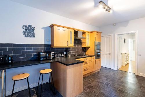 uma cozinha com armários de madeira e bancadas pretas em Contractor & Leisure & Garden & Central Location em Grimsby