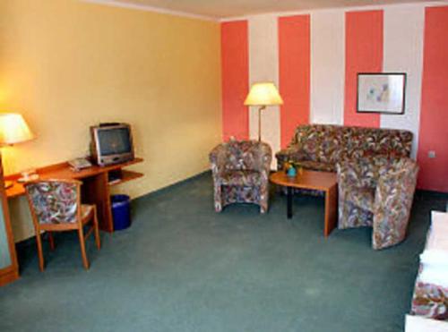 a room with a couch and a table and a tv at TOP Motel Sassnitz in Lanken