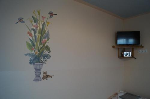 a vase of flowers on a wall next to a tv at Ostoja in Polańczyk