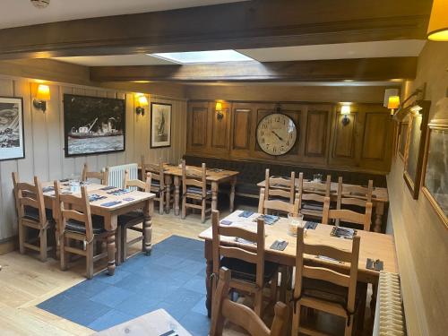 a restaurant with wooden tables and a clock on the wall at Garddfon Inn in Y Felinheli
