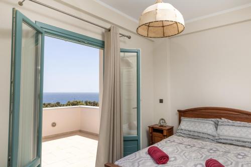 a bedroom with a bed and a balcony with the ocean at Ligaridia Apartments in Moutsoúna