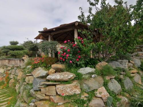 a stone wall with flowers and a gazebo at Logement de charme avec piscine privative in Pino