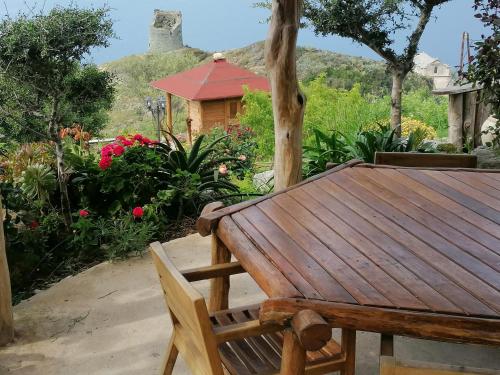 a wooden table and bench in a garden at Logement de charme avec piscine privative in Pino