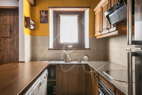 a kitchen with wooden cabinets and a sink and a window at Casa Nere by SeaMount Rentals in Salardú