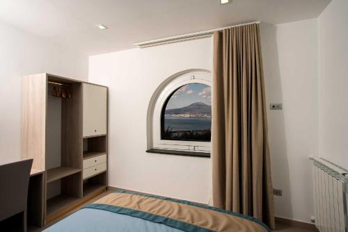 1 dormitorio con espejo, cama y ventana en Charme en Bleu, en Castellammare di Stabia