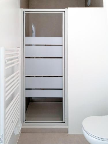 a bathroom with a white closet with glass doors at DUNKE in Dunkerque