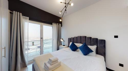 a bedroom with a bed with blue pillows and a window at Key View - Lake View in Dubai