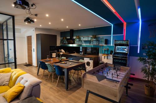 a living room with a table and a kitchen with blue at Capsule Gaming balnéo & billard & babyfoot & sauna 2 chambres in Valenciennes