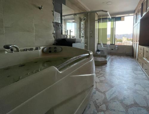 ein Badezimmer mit einer Badewanne und einem großen Spiegel in der Unterkunft Hotel Airport Travel in Bogotá