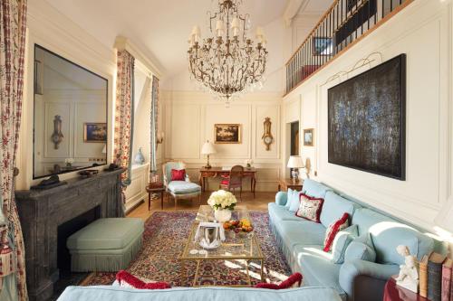 a living room with a blue couch and a chandelier at Beau-Rivage Genève in Geneva