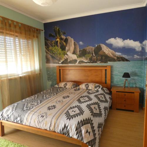a bedroom with a bed with a painting on the wall at Casa do Quebrado in Peniche