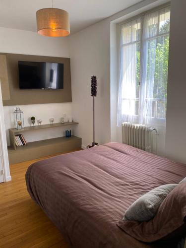une chambre avec un grand lit et une télévision à écran plat dans l'établissement Le Jardin du saumon, à Angé