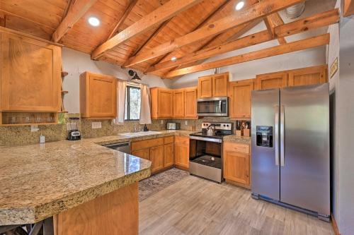 a kitchen with wooden cabinets and a stainless steel refrigerator at Cabin in Tonto National Forest Deck and Views! in Pine