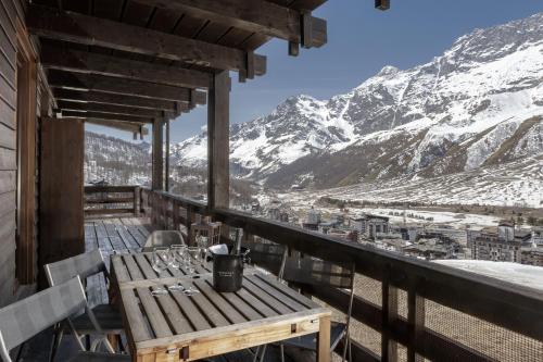 einen Tisch und Stühle auf einem Balkon mit schneebedeckten Bergen in der Unterkunft HelloChalet - Ski paradise Apartment - Ski- to door with big terrace overlooking skiruns in Breuil-Cervinia
