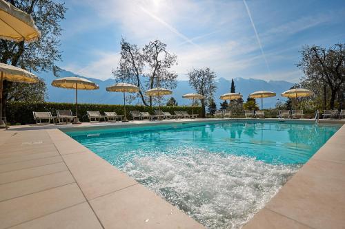 a swimming pool with chairs and umbrellas at Hotel Rosemarie in Limone sul Garda