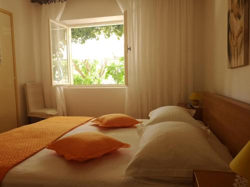 a bed with pillows and a window in a room at Apartments & Rooms Anita in Hvar