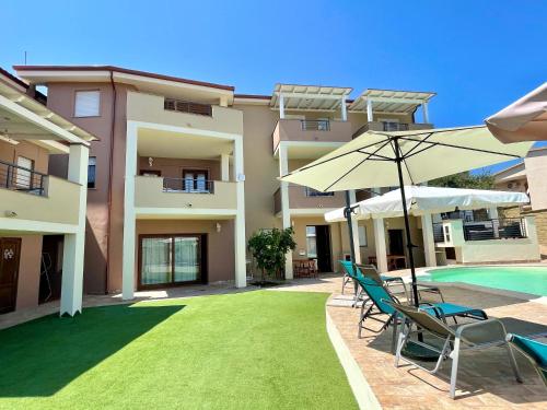 a pool with chairs and umbrellas next to a building at Apartment Maria in Tergu