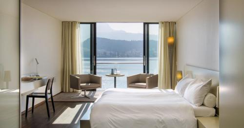 a hotel room with a bed and a view of the water at HERMITAGE Lake Lucerne - Beach Club & Lifestyle Hotel in Luzern