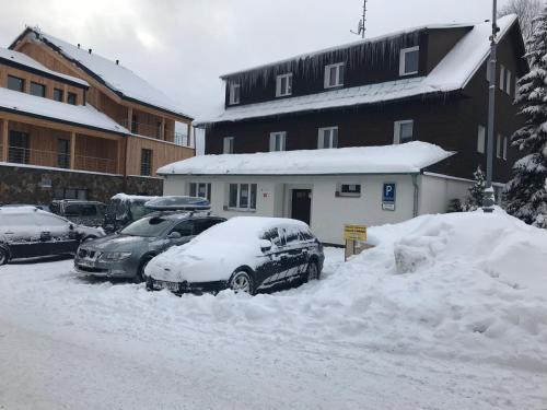 two cars are covered in snow in a parking lot at Zotavovna Kvilda in Kvilda