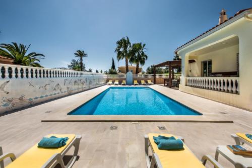 a swimming pool with lounge chairs and a house at 5BR Villa with Private Pool and Snooker Room in Carvoeiro