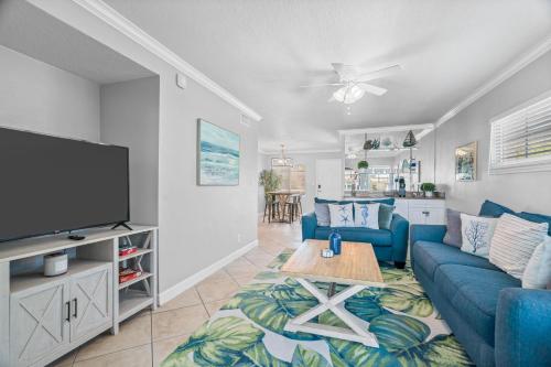 a living room with a blue couch and a tv at Barefoot Breeze in Clearwater Beach