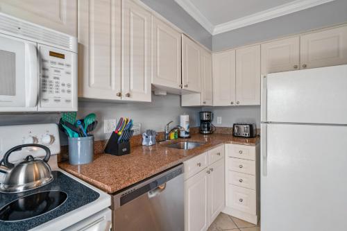 a kitchen with white cabinets and a white refrigerator at Barefoot Breeze in Clearwater Beach