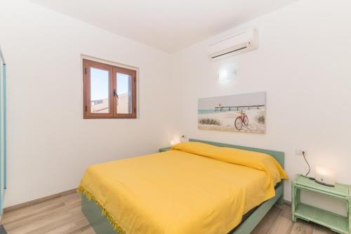 a bedroom with a yellow bed and a window at Flat Orizzonte Rosso in Palau