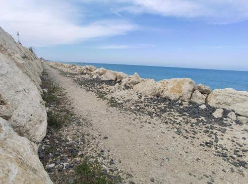 a dirt road next to a rock wall next to the ocean at DolceVita Home in Civitanova Marche