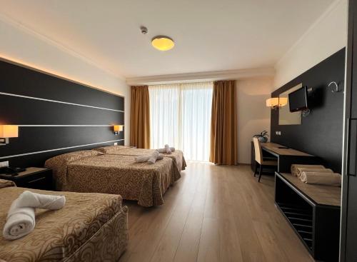 a hotel room with two beds and a desk at Village Bazzanega - Montagnoli Group in Tremosine Sul Garda