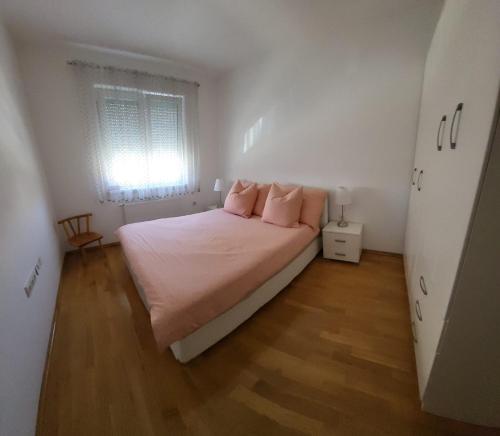 Un dormitorio con una cama con almohadas rosas. en Apartman Pati, en Livno