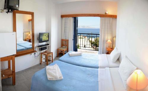 una camera d'albergo con due letti e uno specchio di Hotel Maria-Elena ad Agios Kirykos