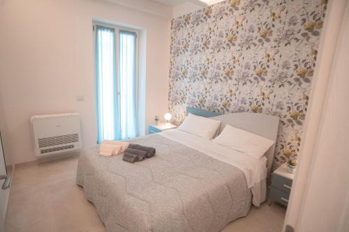 - une chambre avec un lit blanc et un mur fleuri dans l'établissement Le Camelie -appartamenti nuovi, à Porto SantʼElpidio