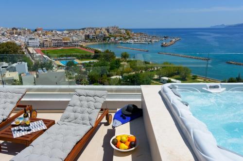 a balcony with a pool and chairs and a bowl of fruit at Angelique Luxury apartment in Agios Nikolaos