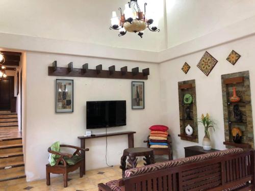 sala de estar con sofá y TV de pantalla plana en Tagaytay BNR Guesthouse 4BR With Balcony 12-14 Guest, en Tagaytay