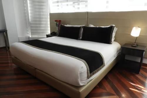 a large white bed with black pillows in a room at Hotel Airport Travel in Bogotá