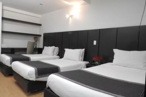 a hotel room with three beds in a room at Hotel Airport Travel in Bogotá
