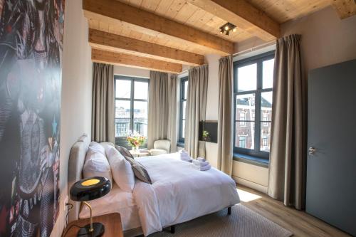 Schlafzimmer mit einem großen weißen Bett und Fenstern in der Unterkunft Bistrotel 't Amsterdammertje in Nieuwersluis