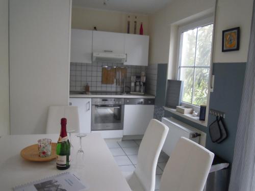 a kitchen with white cabinets and a table with white chairs at Lenzer Parkblick am Plauer See in Lenz