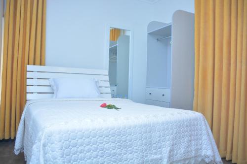 a bedroom with a white bed with a flower on it at ARAUCARIA RESIDENCE in Gisenyi