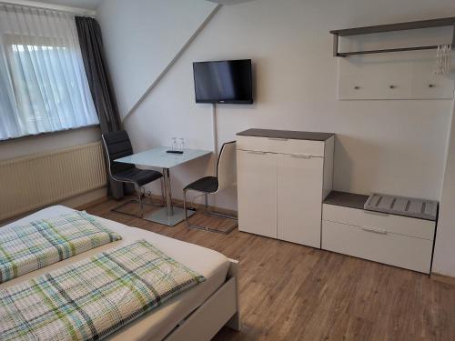 a bedroom with a bed and a table and a tv at Pension am Wald in Gößweinstein